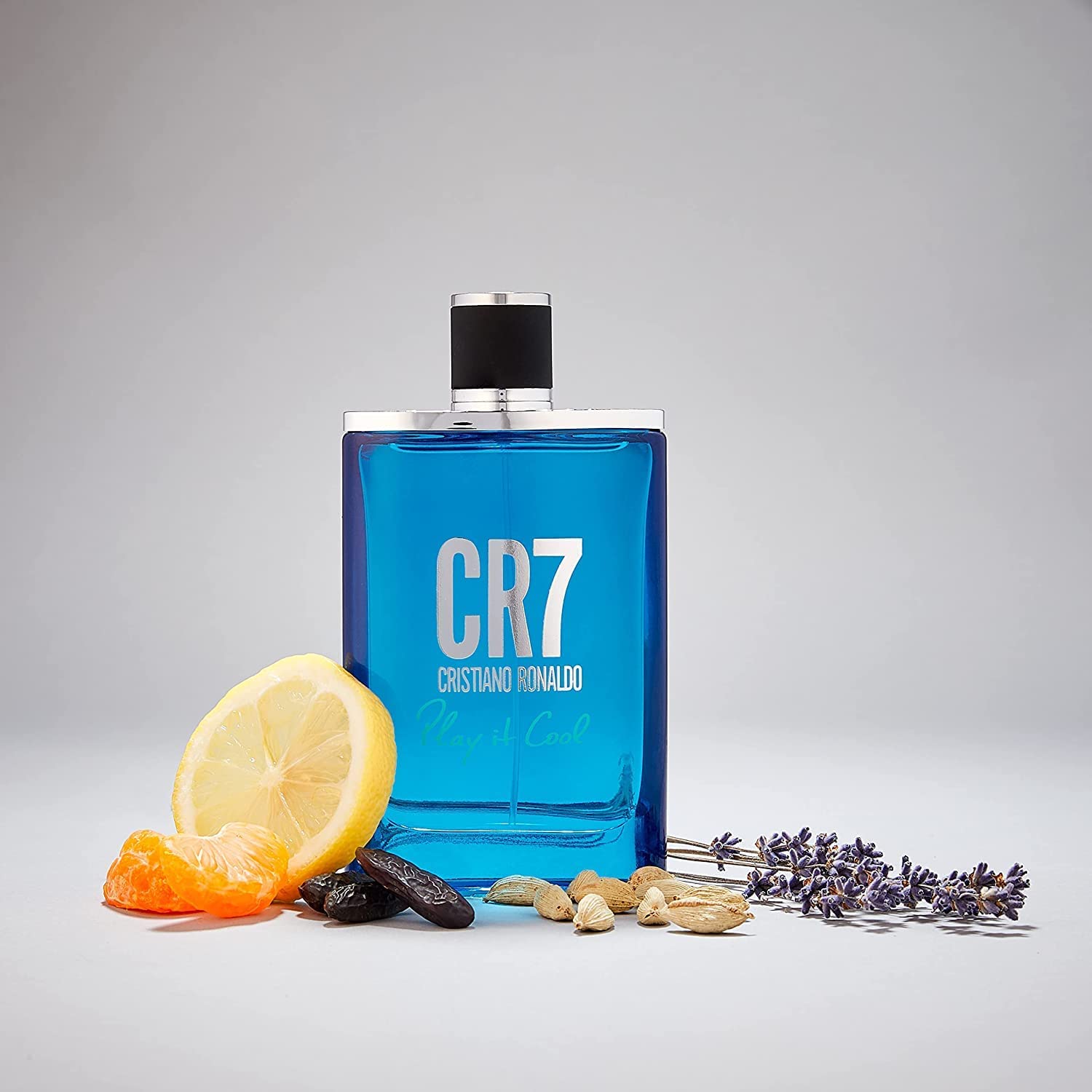 CR7 Cristiano Ronaldo Play It Cool Eau De Toilette - A bottle of refreshing blue liquid accompanied by a selection of dried fruit. This unique fragrance combines light, fresh notes with a sophisticated composition, perfect for everyday wear. An energizing citrus and herbal aroma, designed for the active and energetic man.